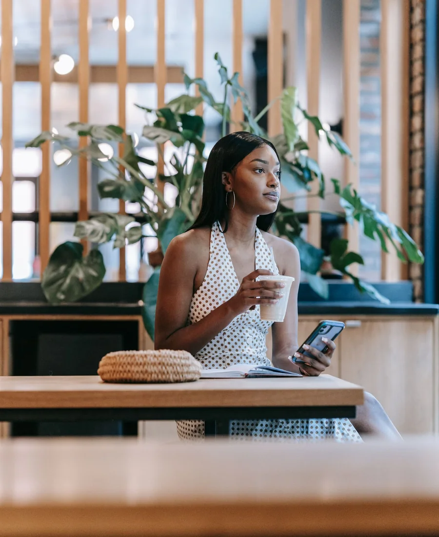 A woman taking a moment to enjoy her coffee and check her phone